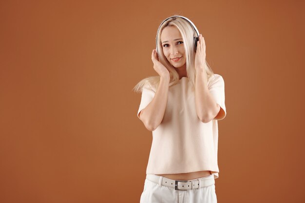 Mujer joven feliz en ropa casual disfrutando de escuchar música en auriculares