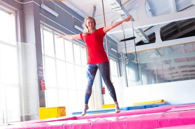 Mujer joven feliz saltando en un trampolín en el interior.