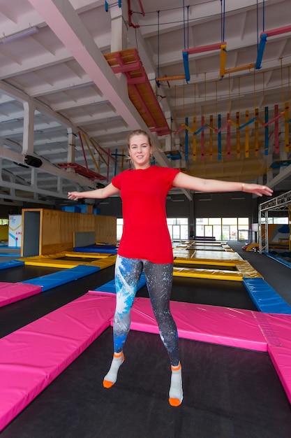 Mujer joven feliz saltando en un trampolín en el interior.