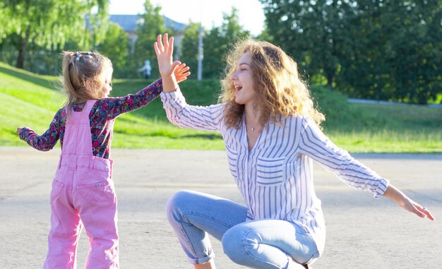 Mujer joven feliz sentada jugando con una niña aplaudiendo