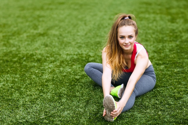 Mujer joven feliz sentado al aire libre en posición de yoga