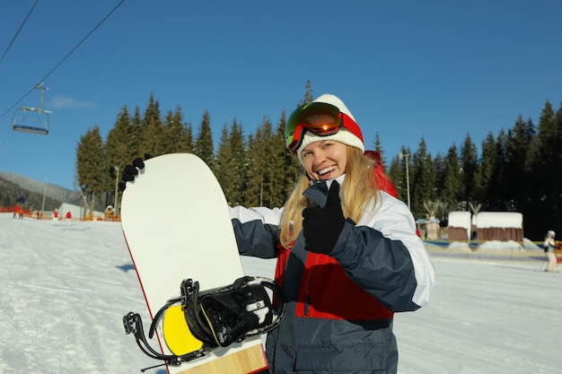 Mujer joven feliz con snowboard en mountain resort