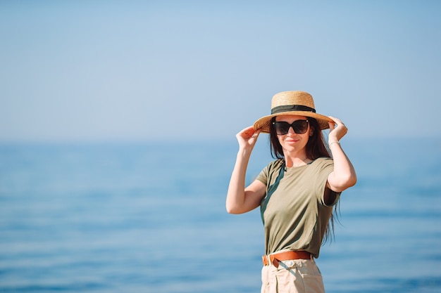 Mujer joven feliz con sombrero en la playa blanca