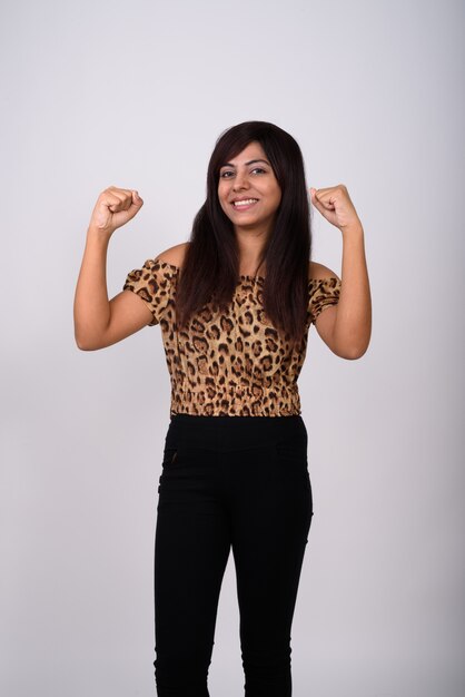 Mujer joven feliz sonriendo mientras está de pie y flexionando ambos brazos