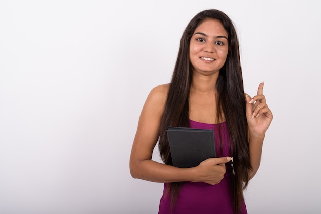 Mujer joven feliz sonriendo mientras sostiene el libro y apuntando con el dedo hacia arriba