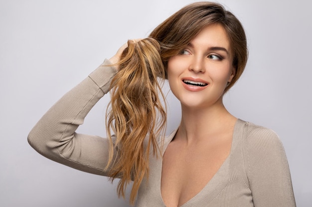 Foto mujer joven está feliz con su cabello hermoso y saludable sobre fondo gris