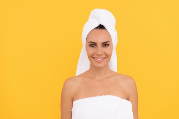 Mujer joven feliz con toalla después de la ducha sobre fondo amarillo