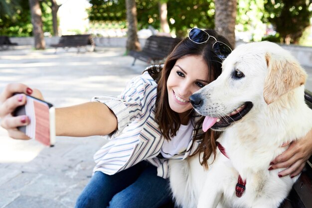 Mujer joven feliz tomando selfie con su perro