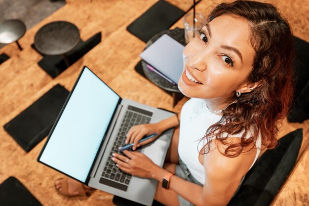 Mujer joven feliz trabajando en un portátil con pantalla en blanco en blanco