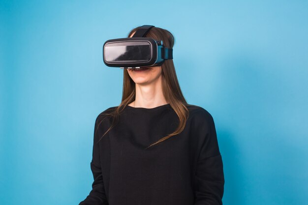 Mujer joven feliz usando un casco de realidad virtual en azul