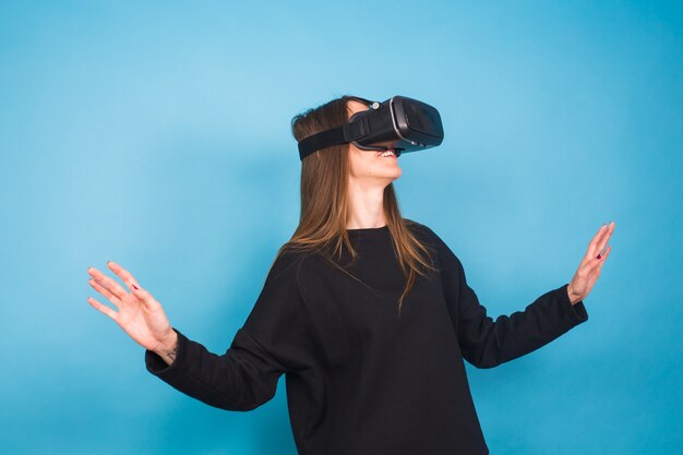 Mujer joven feliz usando un casco de realidad virtual en azul