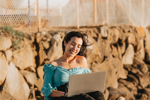 Mujer joven feliz usando su computadora portátil en los muelles