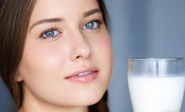 Mujer joven feliz con un vaso de leche o un batido de proteínas, un cóctel saludable para la dieta y el bienestar