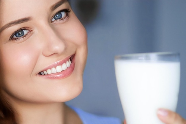 Mujer joven feliz con un vaso de leche o un batido de proteínas, un cóctel saludable para la dieta y el bienestar