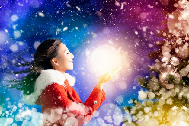 Mujer joven feliz viendo la bola de luz y el fondo de Navidad