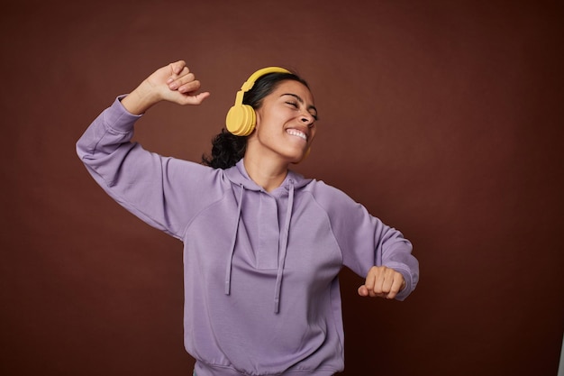 Mujer joven felizmente disfrutando de la música en el móvil con auriculares