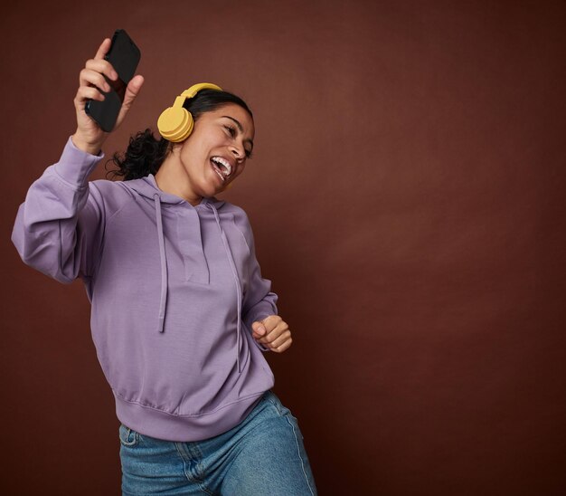 Mujer joven felizmente disfrutando de la música en el móvil con auriculares