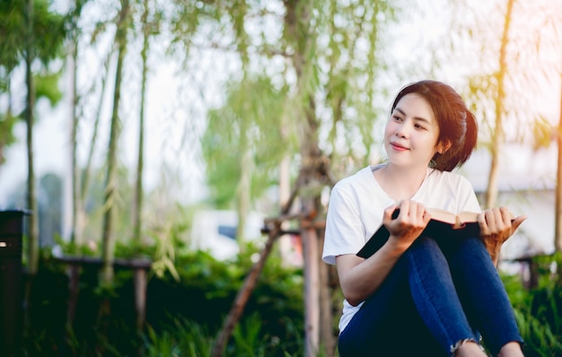 Mujer joven felizmente leyendo el libro en la naturaleza