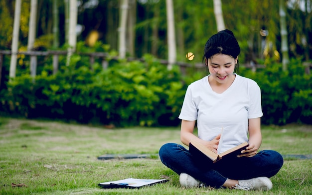 Mujer joven felizmente leyendo el libro en la naturaleza