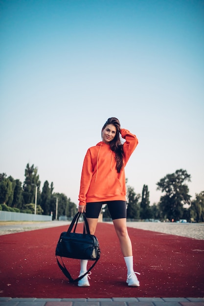 Mujer joven fitness con bolsa en campo de deportes