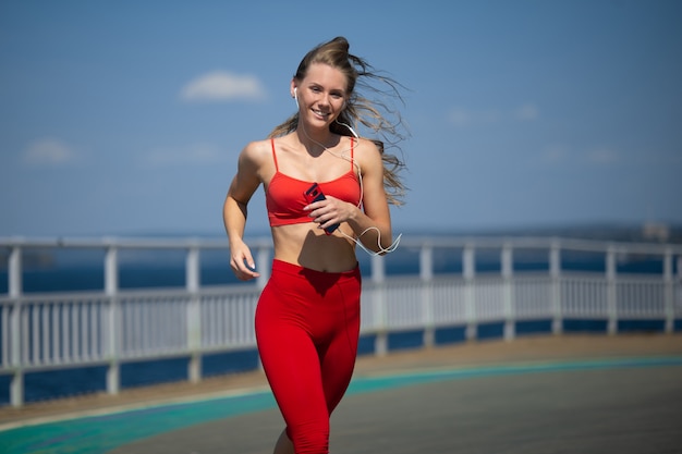 Mujer joven fitness correr en la costa. El concepto de un estilo de vida saludable.