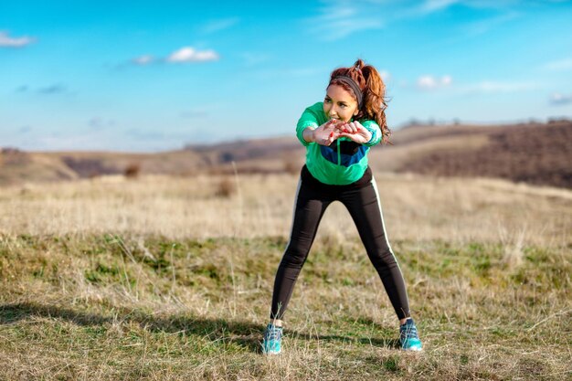 Foto mujer joven fitness haciendo ejercicio de estiramiento después de trotar en la naturaleza.