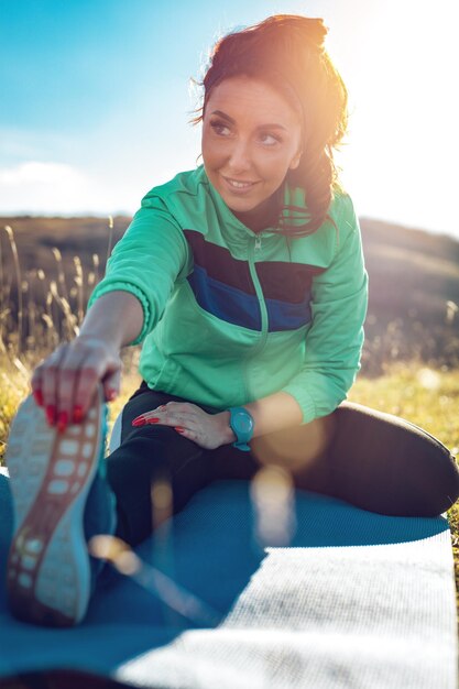 Mujer joven fitness haciendo ejercicio de estiramiento después de trotar en la naturaleza.