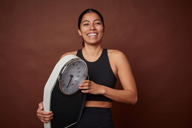 Mujer joven fitness midiendo el progreso con una escala para una vida saludable