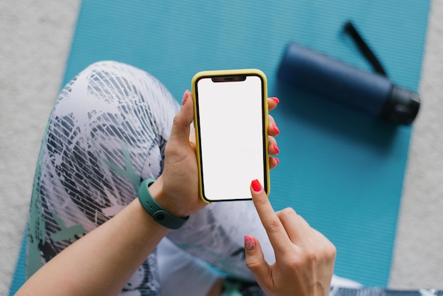 Mujer joven fitness mira y mete el dedo en el teléfono Deportes y fitness en casa