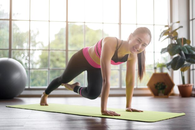 Mujer joven fitness en ropa deportiva haciendo ejercicio en casa saludable y estilos de vida