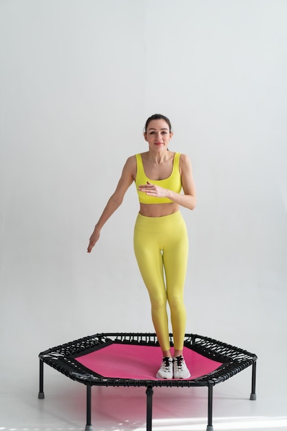 Mujer joven fitness en ropa deportiva saltando en trampolín deportivo