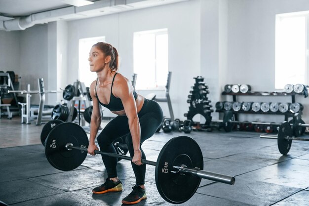 Mujer joven de fitness con tipo de cuerpo delgado haciendo ejercicios con barra