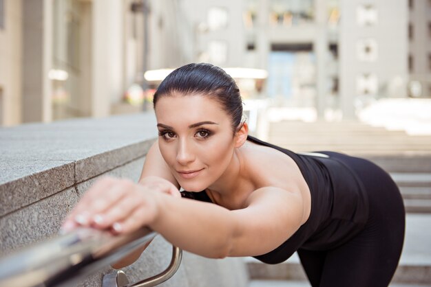 Mujer joven flexible apoyado en la barandilla