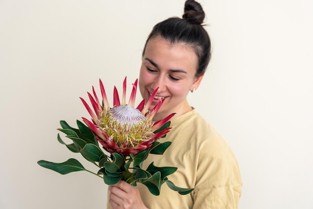 Una mujer joven con flor protea sobre un fondo blanco.