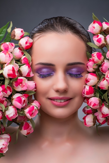 Mujer joven con flores en concepto de belleza