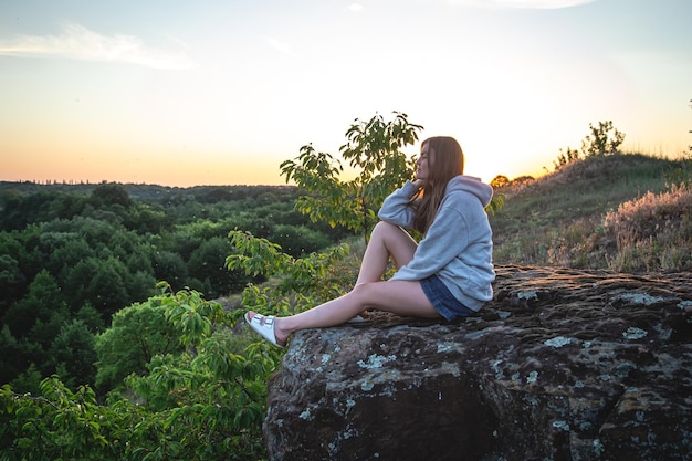 Una mujer joven en el fondo de un paisaje forestal en una zona montañosa.