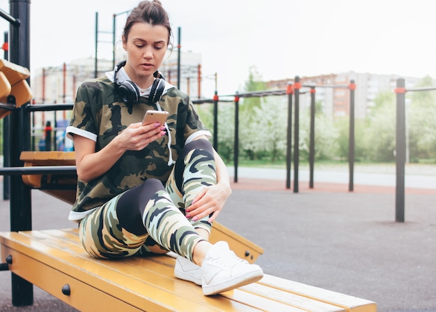 fragancia Unión habla Mujer joven en forma atractiva en ropa deportiva de color militar haciendo  entrenamiento con el móvil en el área de entrenamiento de la calle. | Foto  Premium