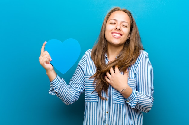 Mujer joven con forma de corazón contra azul