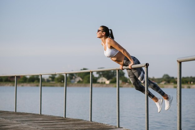 Mujer joven en forma delgada haciendo ejercicio deportivo al aire libre en el parque en el día soleado