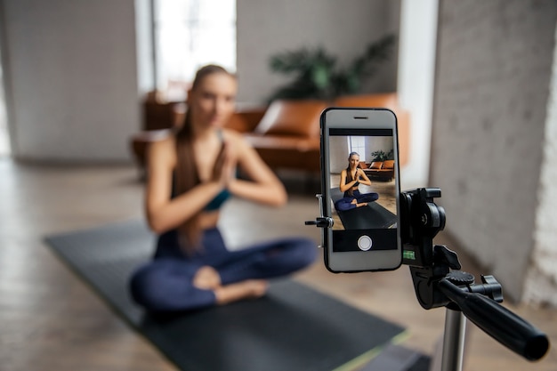 Mujer joven en forma de meditación blogger y grabación de traducción en línea por teléfono. Concepto vivo. Foto de alta calidad