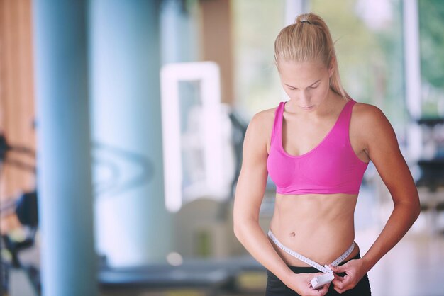 mujer joven en forma midiendo el vientre en un entrenamiento en el gimnasio