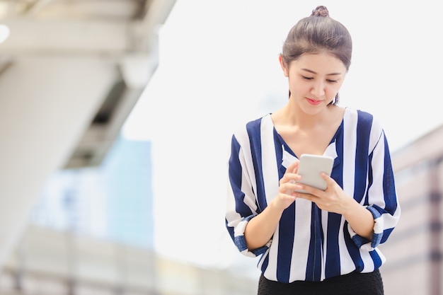 Foto mujer joven de la forma de vida al aire libre que mira en smartphone. concepto de negocio