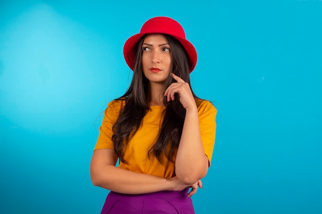 Mujer joven en foto de estudio y en ropa colorida y sombrero rojo