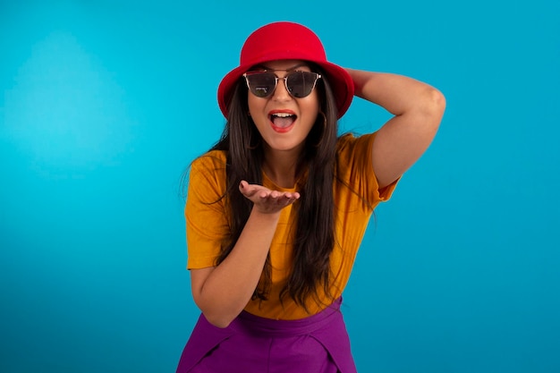 Foto mujer joven en foto de estudio y en ropa colorida y sombrero rojo