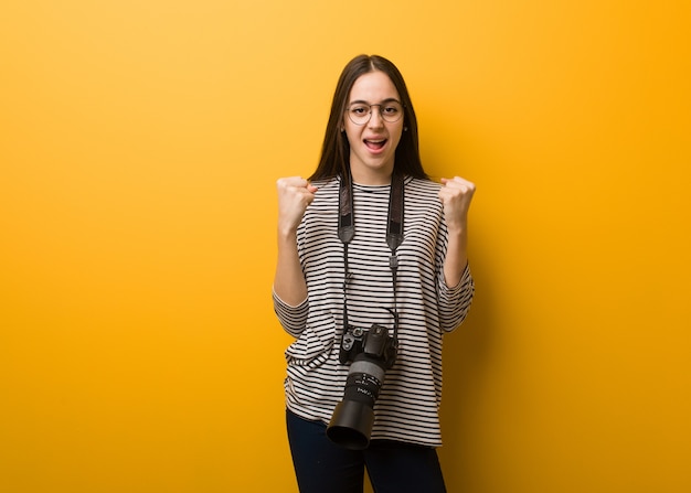 Mujer joven fotógrafo gritando muy enojado y agresivo