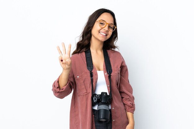 Mujer joven fotógrafo sobre blanco aislado feliz y contando tres con los dedos