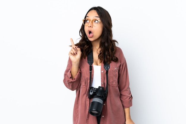 Mujer joven fotógrafo sobre blanco aislado pensando en una idea apuntando con el dedo hacia arriba