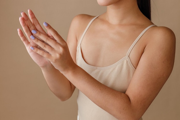 Mujer joven frotando crema cosmética en las manos