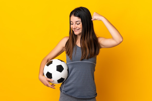 Mujer joven futbolista aislada en amarillo celebrando una victoria