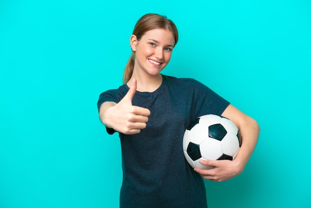 Mujer joven futbolista aislada de fondo azul con los pulgares hacia arriba porque algo bueno ha sucedido